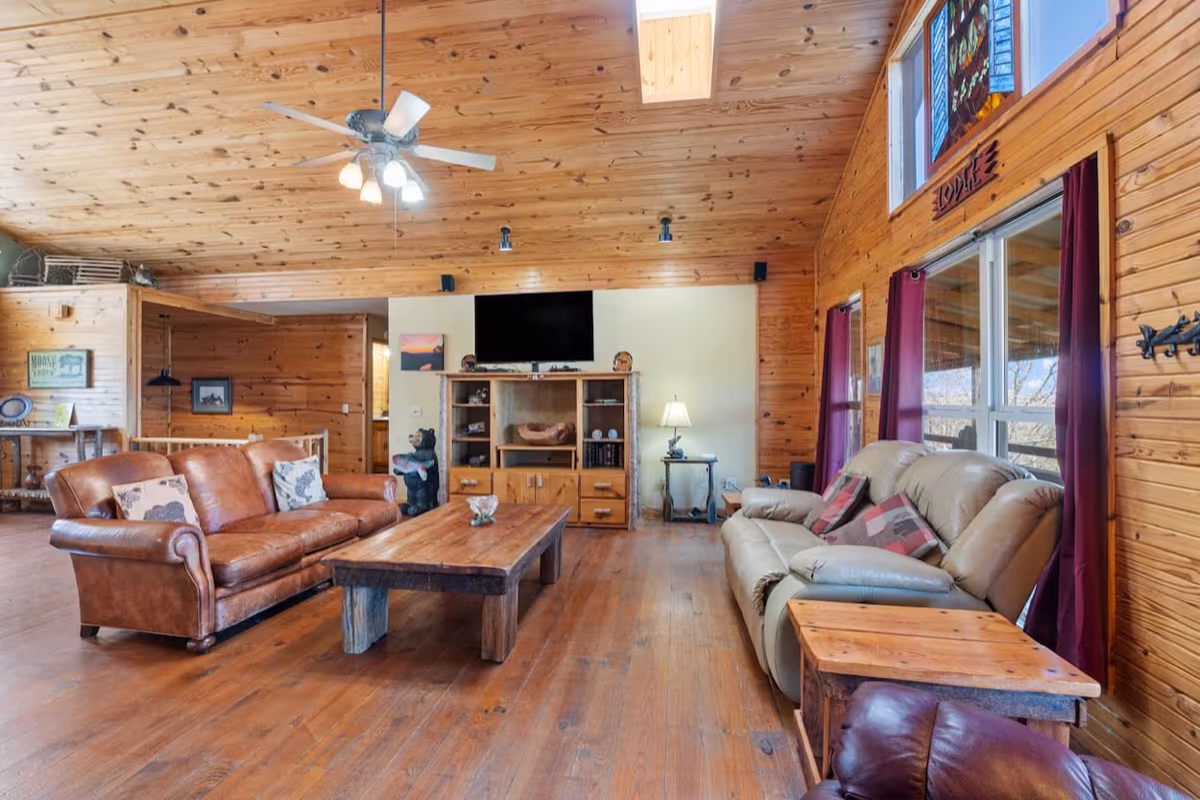 Warm cabin living room with comfortable seating and a large TV